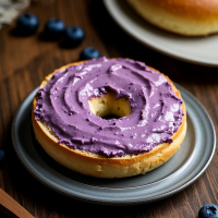 藍莓色起司醬抹在對切的貝果